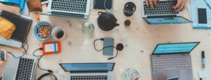 people sitting down near table with assorted laptop computers